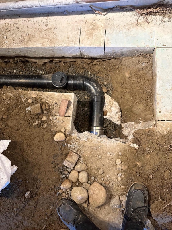 A newly installed ABS sewer line with a cleanout fitting bedded in gravel during a Bee's Plumbing repair in Seattle.