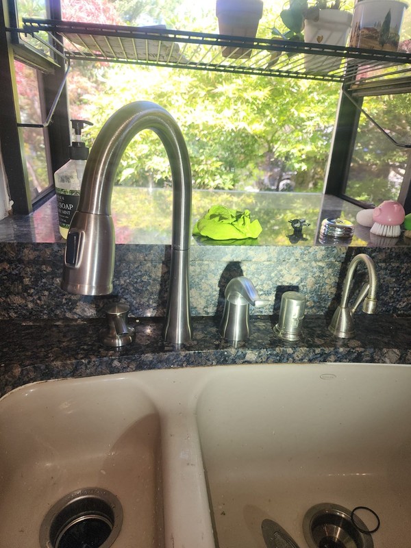 Newly installed brushed stainless pull-down kitchen faucet on a granite countertop in a Seattle, WA home