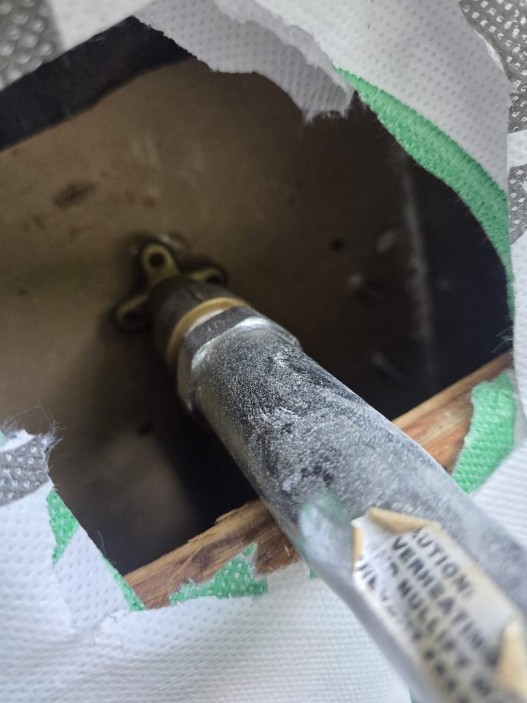 Close-up of the frost-free hose bibb's long stem passing through the wall so the shutoff sits inside the warmer part of the home