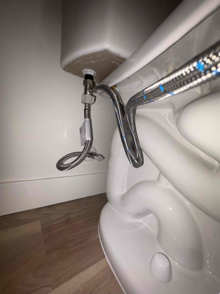 Bidet T-valve and braided supply lines reconnected beneath the toilet tank with no water escaping around the connection