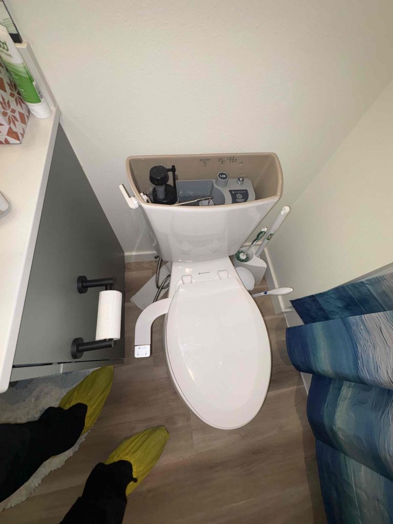 Toilet with the tank lid off and the customer-supplied bidet seat attached, ready for troubleshooting