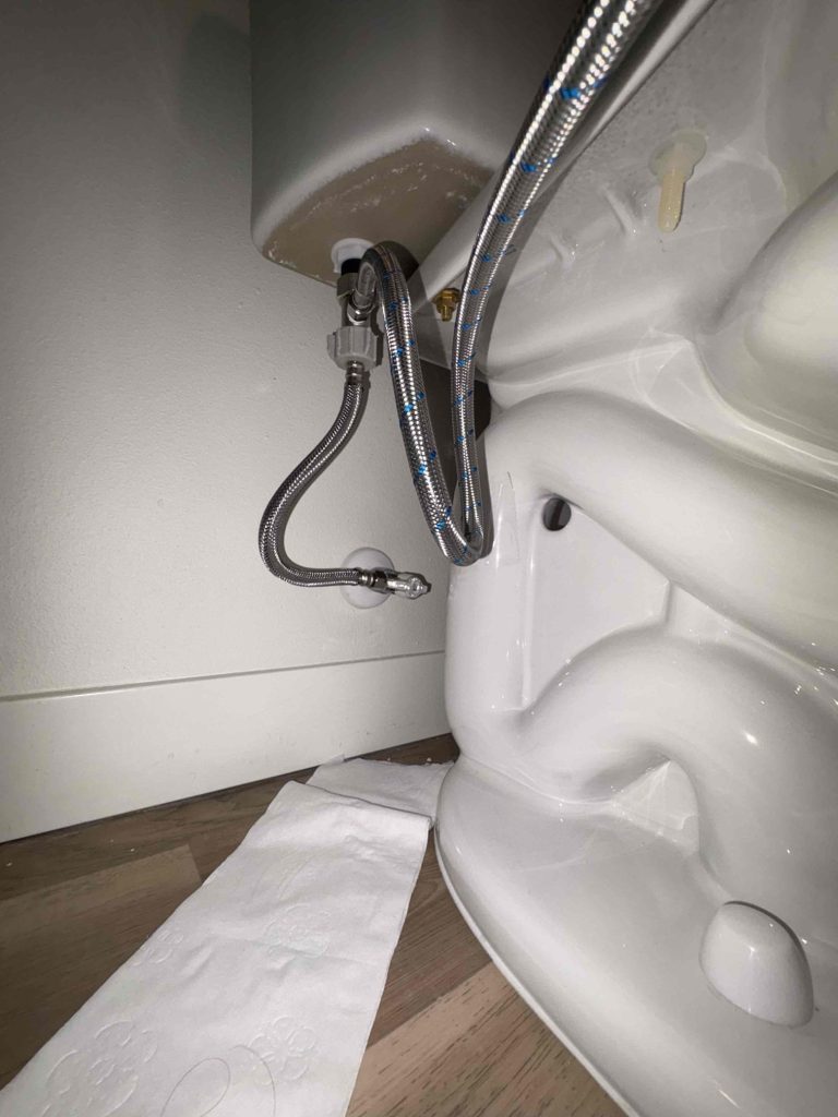 Toilet paper laid on the floor behind the toilet to reveal water escaping at the bidet supply connection in a Seattle, WA home