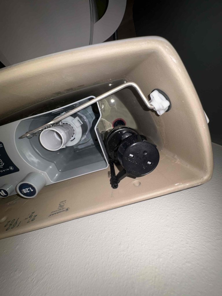 Inside the toilet tank, where the fill valve and flush assembly were checked while tracing the leak