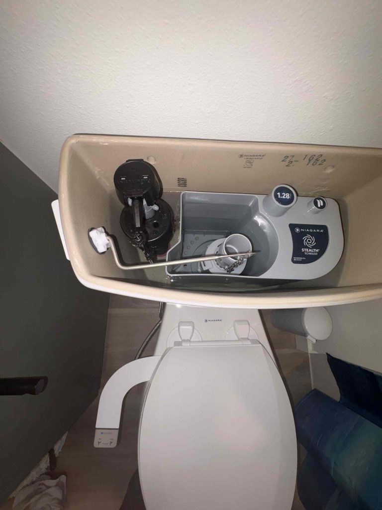 Open toilet tank checked to confirm the toilet was receiving proper water supply through the bidet connection